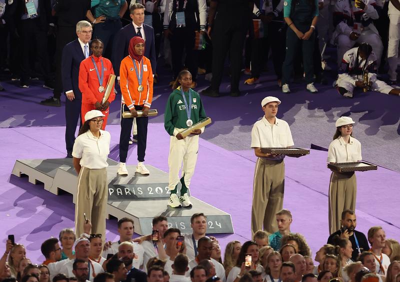 Gold medalist Sifan Hassan (C) of the Netherlands, silver medalist Tigst Assefa (front) of Ethiopia and bronze medalist Hellen Obiri of Kenya attend the victory ceremony of women's marathon of Athletics at the closing ceremony of the Paris 2024 Olympic Games in Paris, France, Aug. 11, 2024. (Xinhua/Zhang Fan)